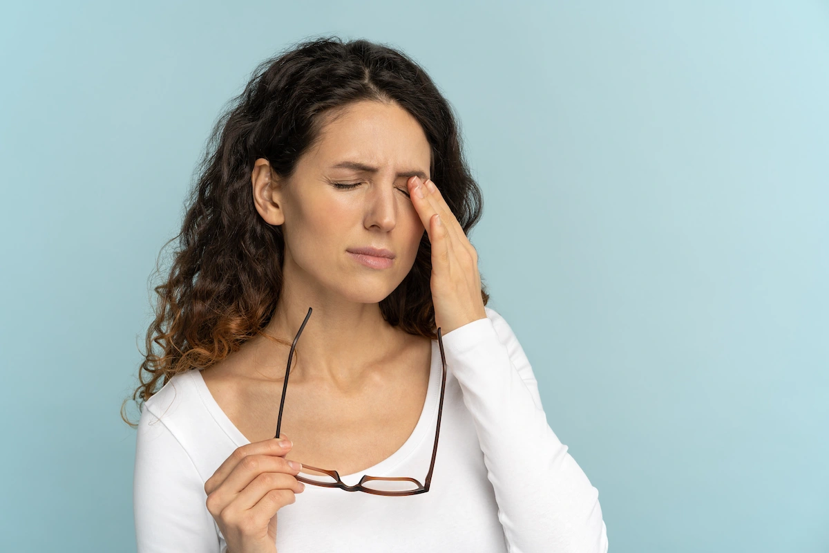woman placing hand on eyelid in pain